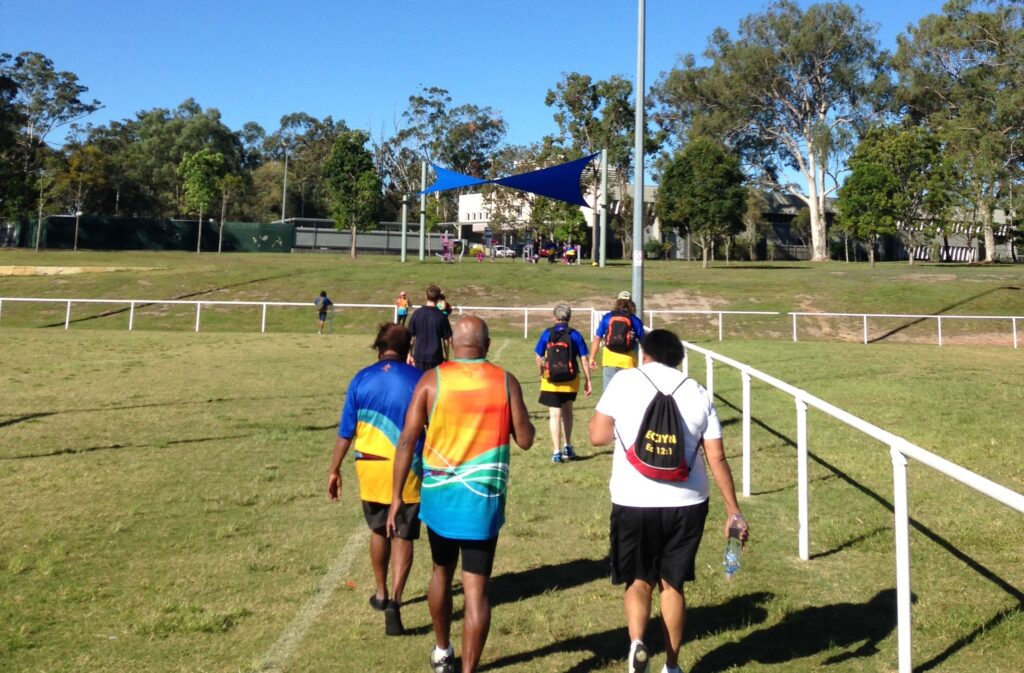 Group of people walking together on a sunny field for fitness activity