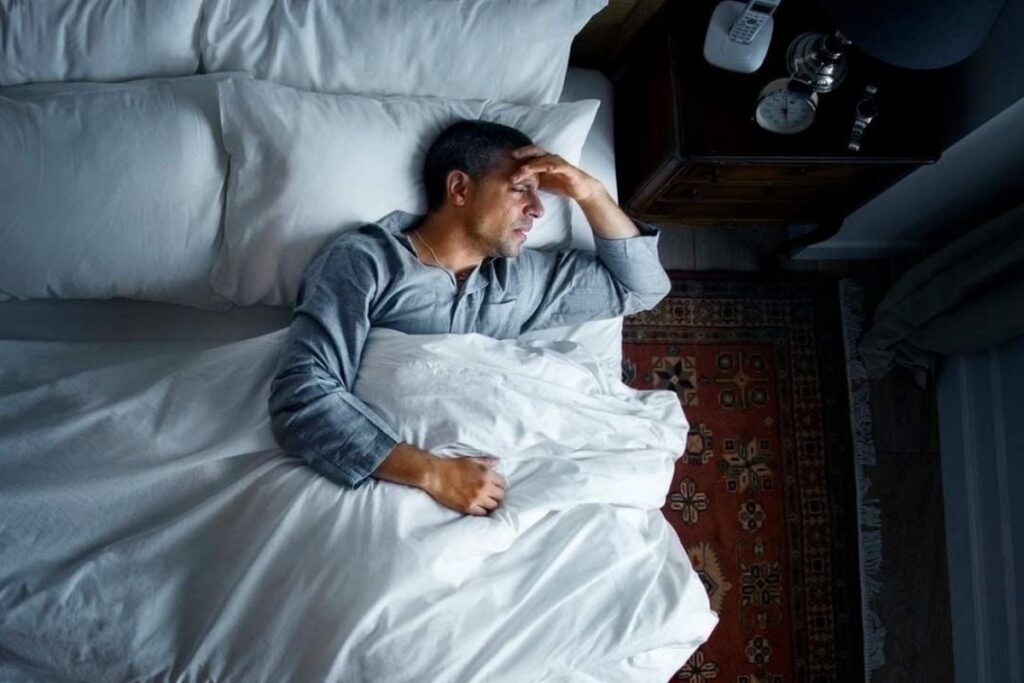 Man lying in bed unable to sleep at night.