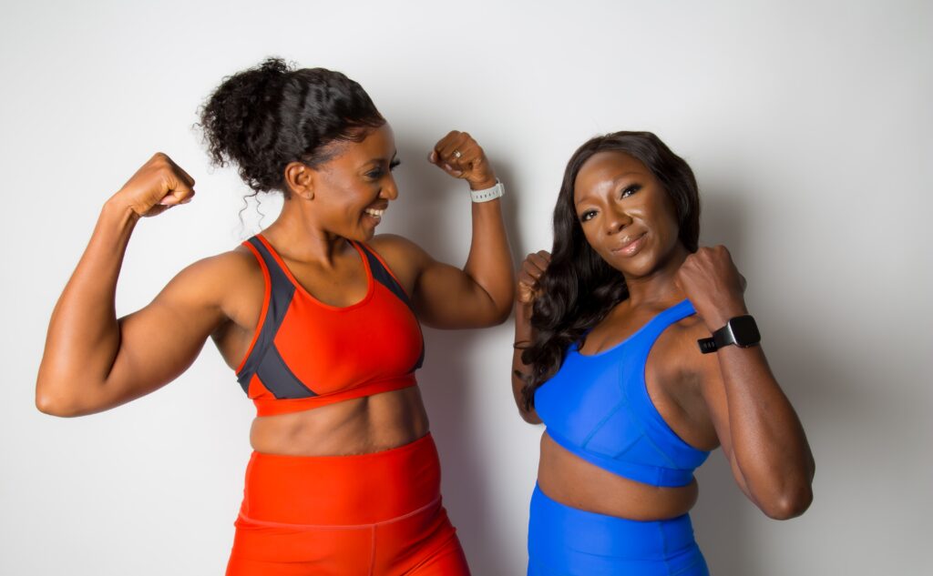 Two women smiling and flexing their arms