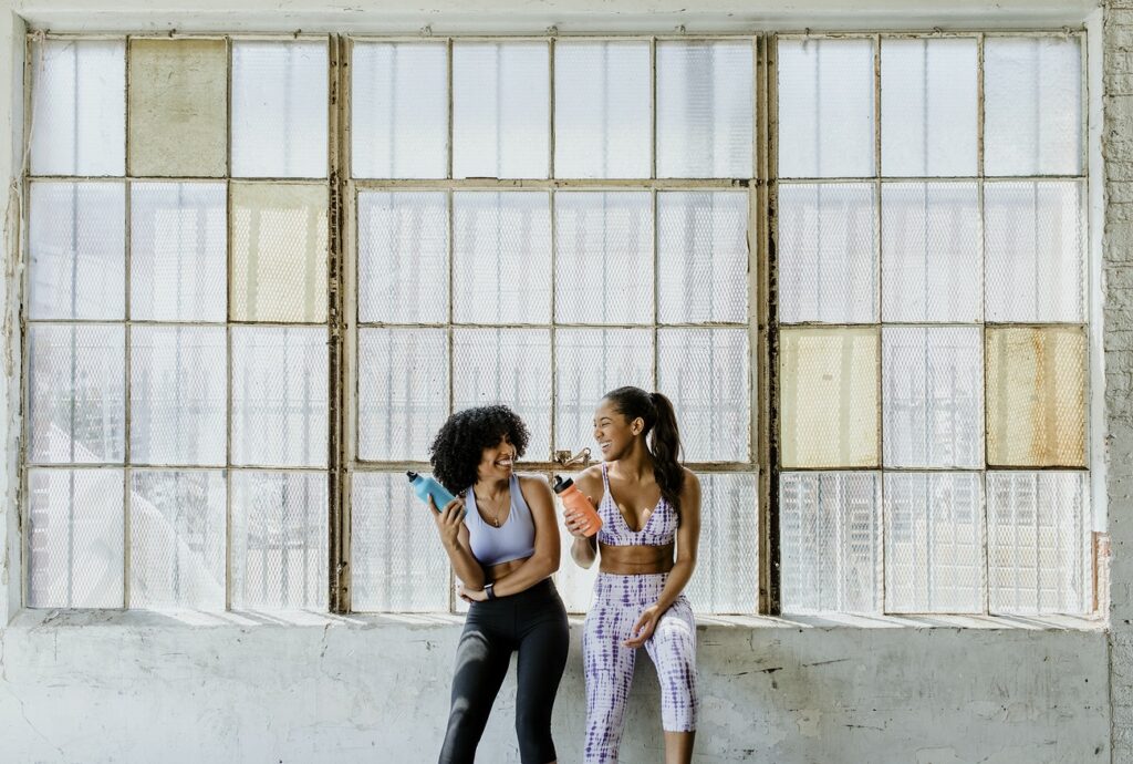 Two women dancing and exercising outdoors with laughter