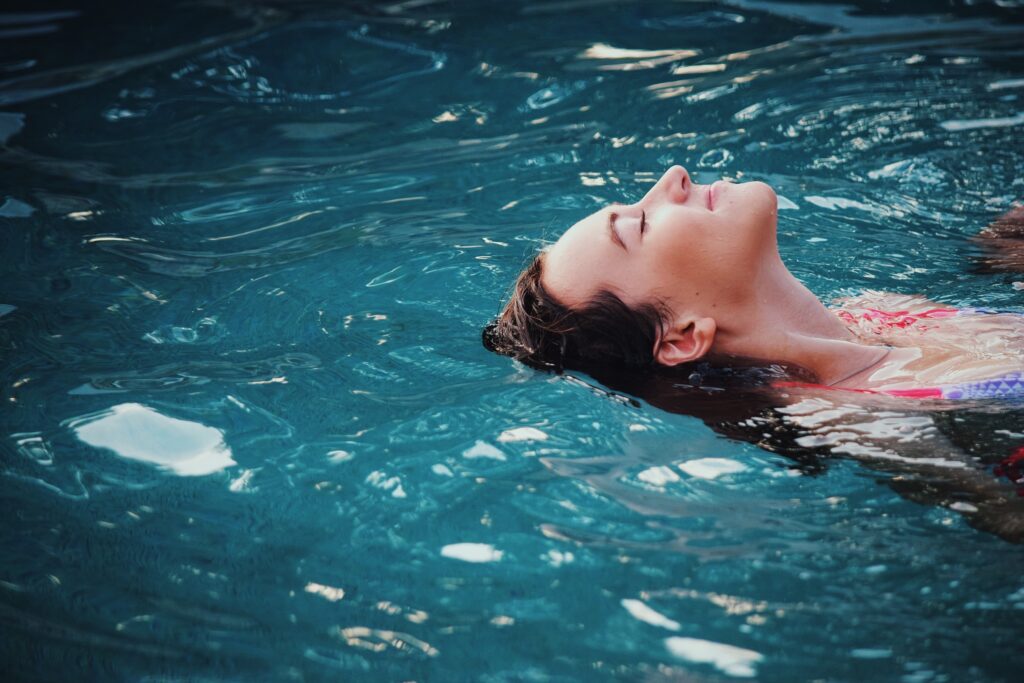 Woman floating calmly in swimming pool practicing relaxation