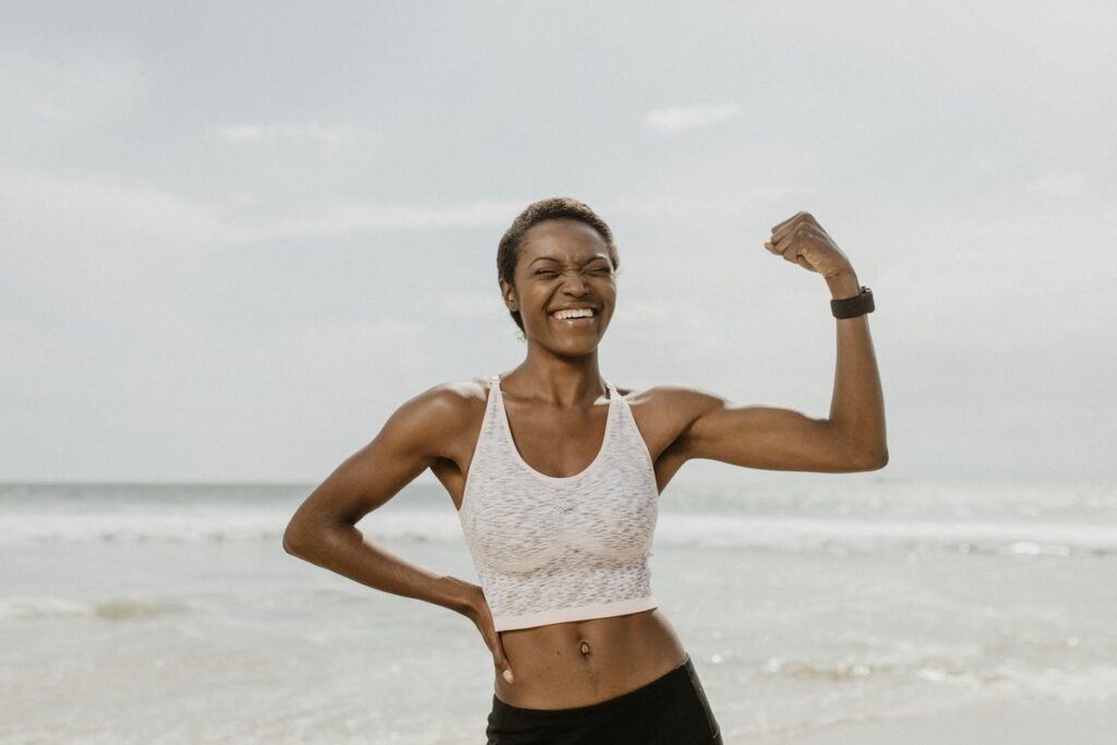 Happy woman stretching arms on beach after workout
