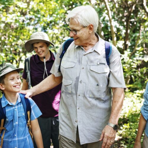 Senior man walking outdoors with his grandchildren, smiling