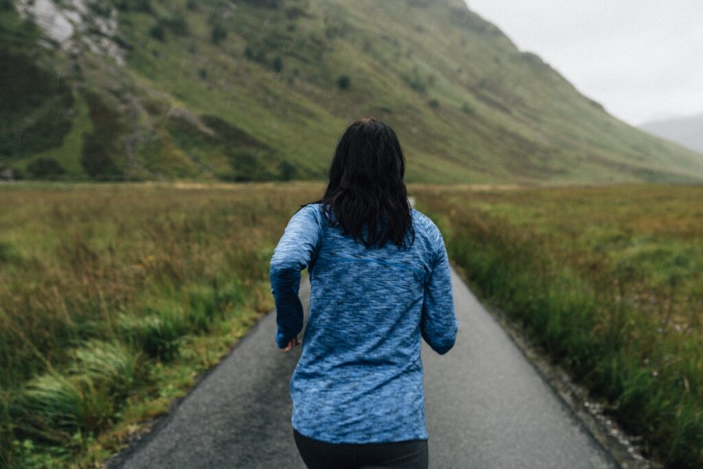 Woman running outdoors on a path surrounded by greenery