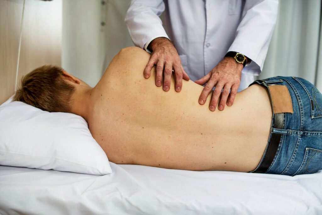 Person receiving back treatment from physiotherapist on massage table