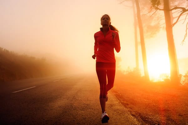 Person running during sunrise on an empty road
